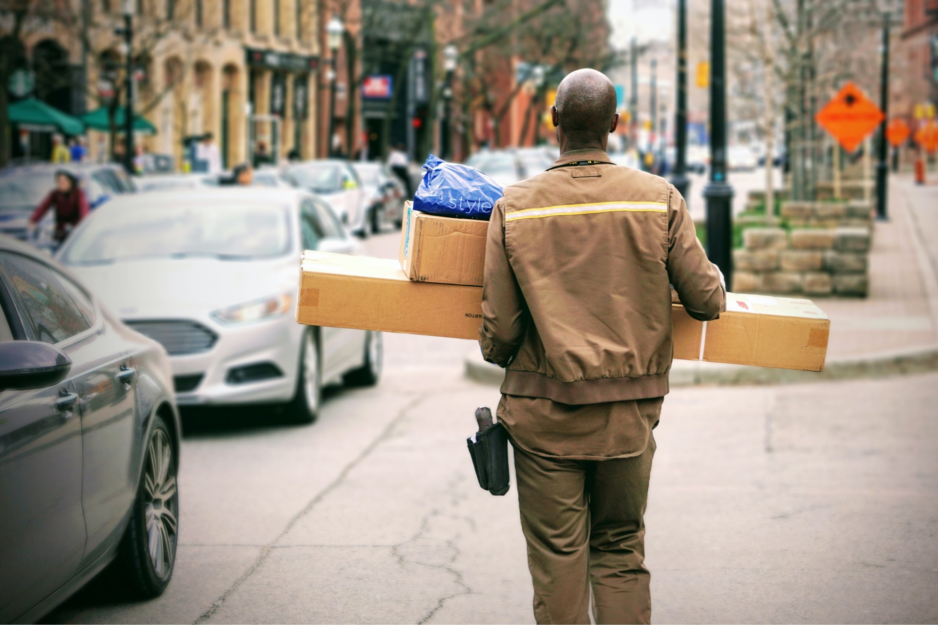 A DHL worker walking holding several parcels.