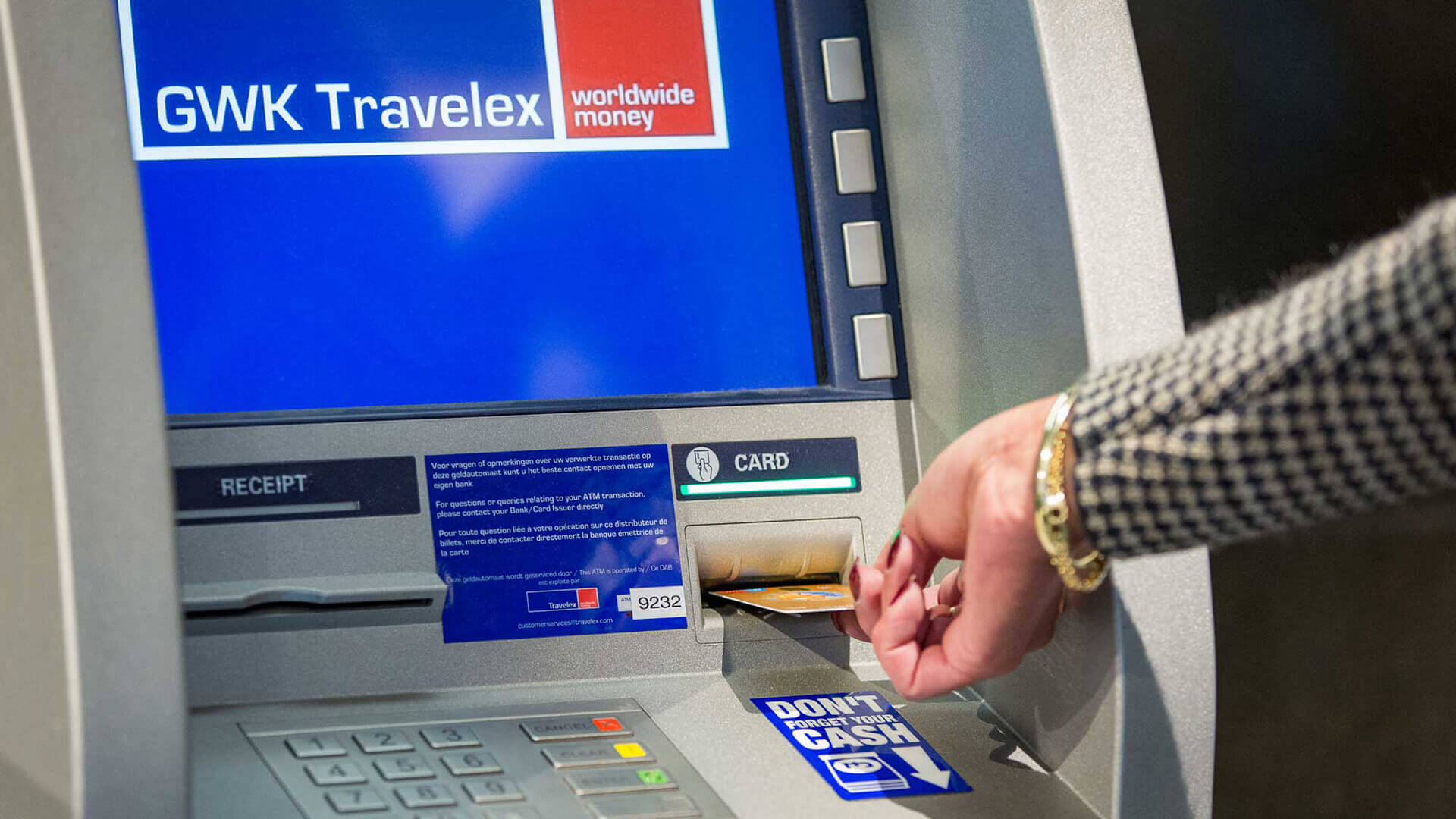 A person holding a credit card on an atm machine.